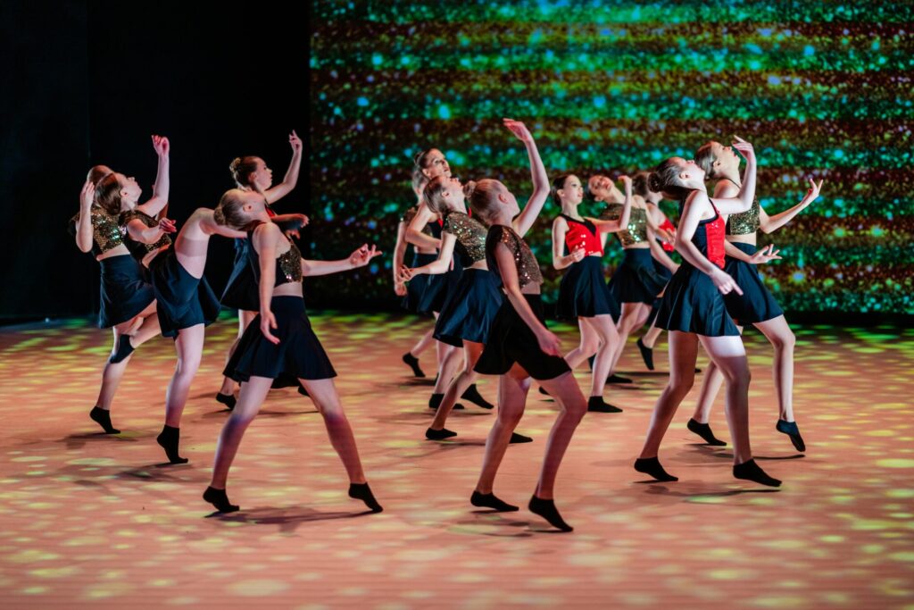 a group of young girls in costumes dancing on a stage