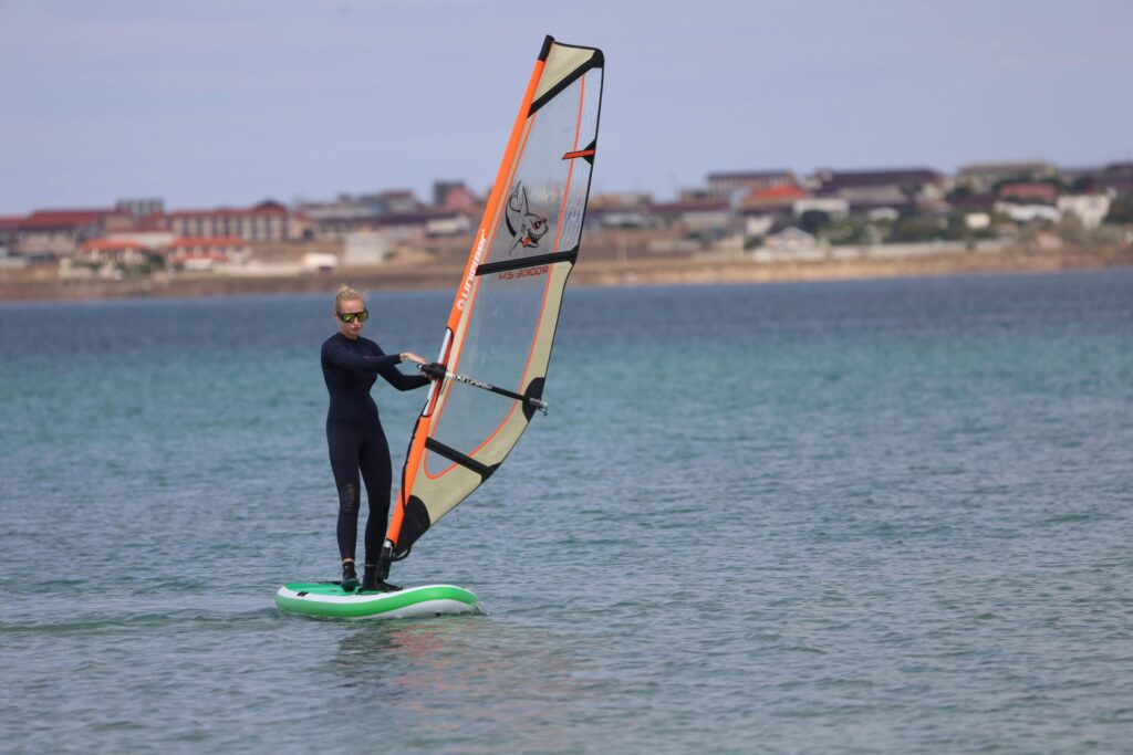 a woman in black wetsuit windsurfing