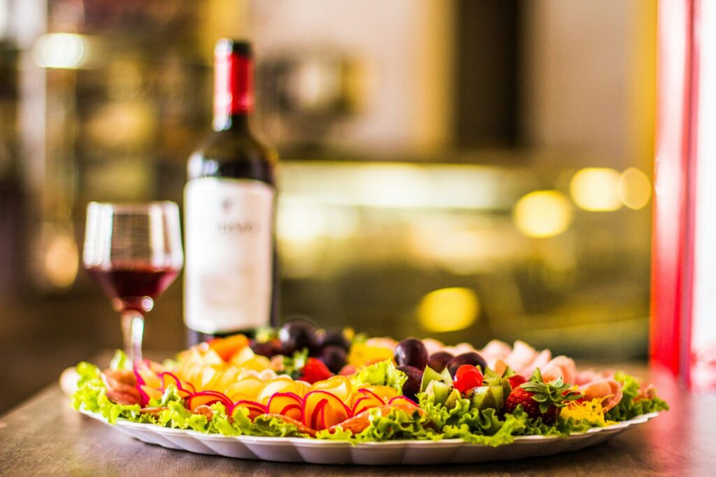 a plate of cold cuts and wine and glass on a wooden table