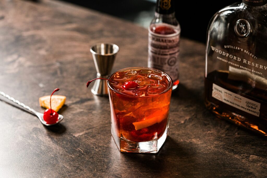 a cocktail with cherries and orange peel on a bar