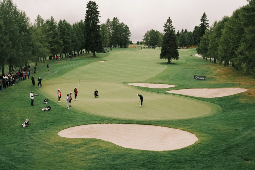 golfers on a green with sand traps and trees