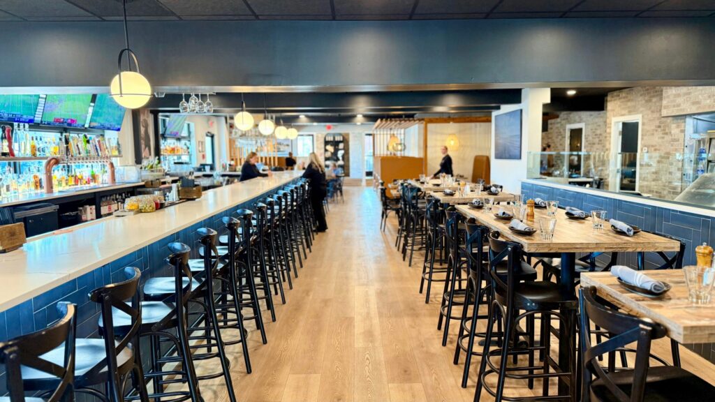 a modern restaurant with a bar and dining tables